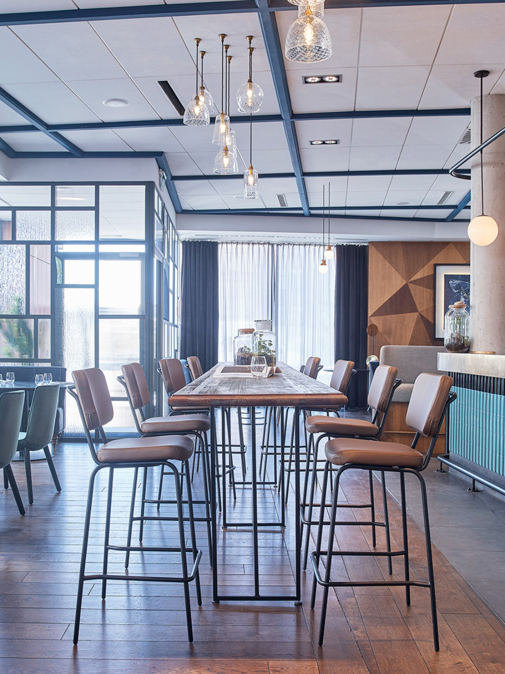 Epocc High Stool with Footrest in Brown Finish with High Table in Restaurant Setting
