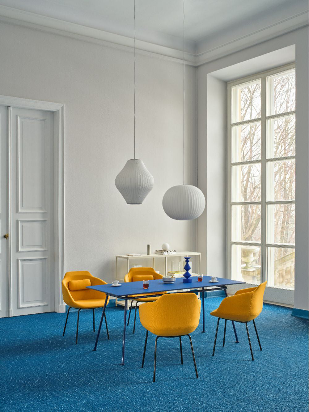 Ultra Office Chair on 4 Legged Metal Legs with Table and Bookshelf in Modern Office Setting