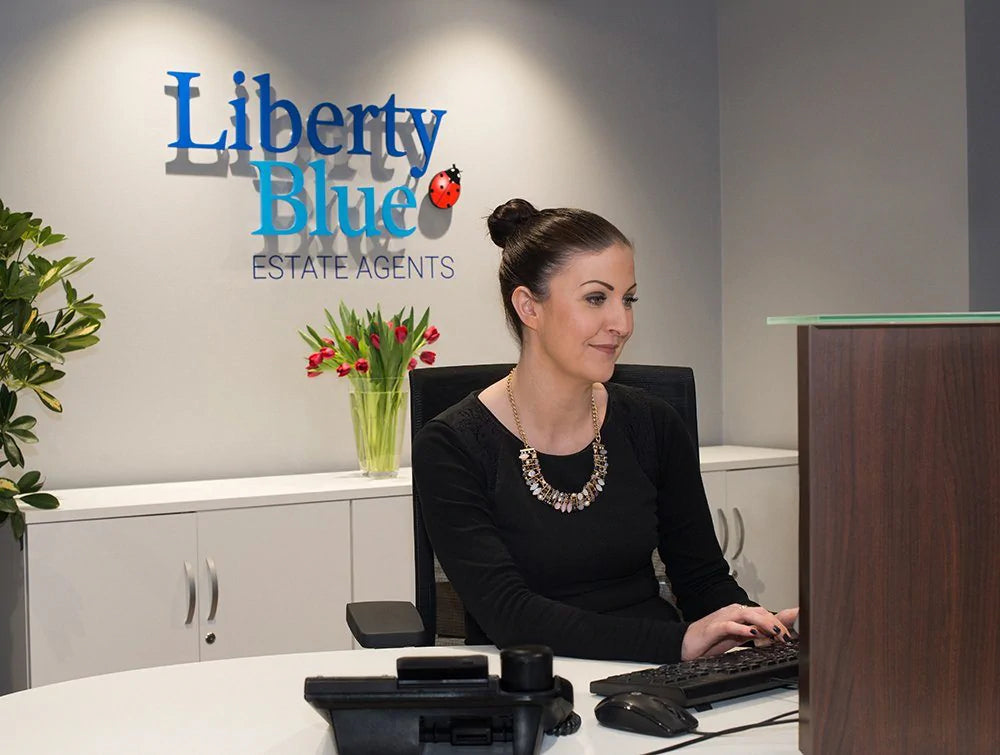 Woman In Black Typing On Keyboard In Front Of Liberty Blue Logo